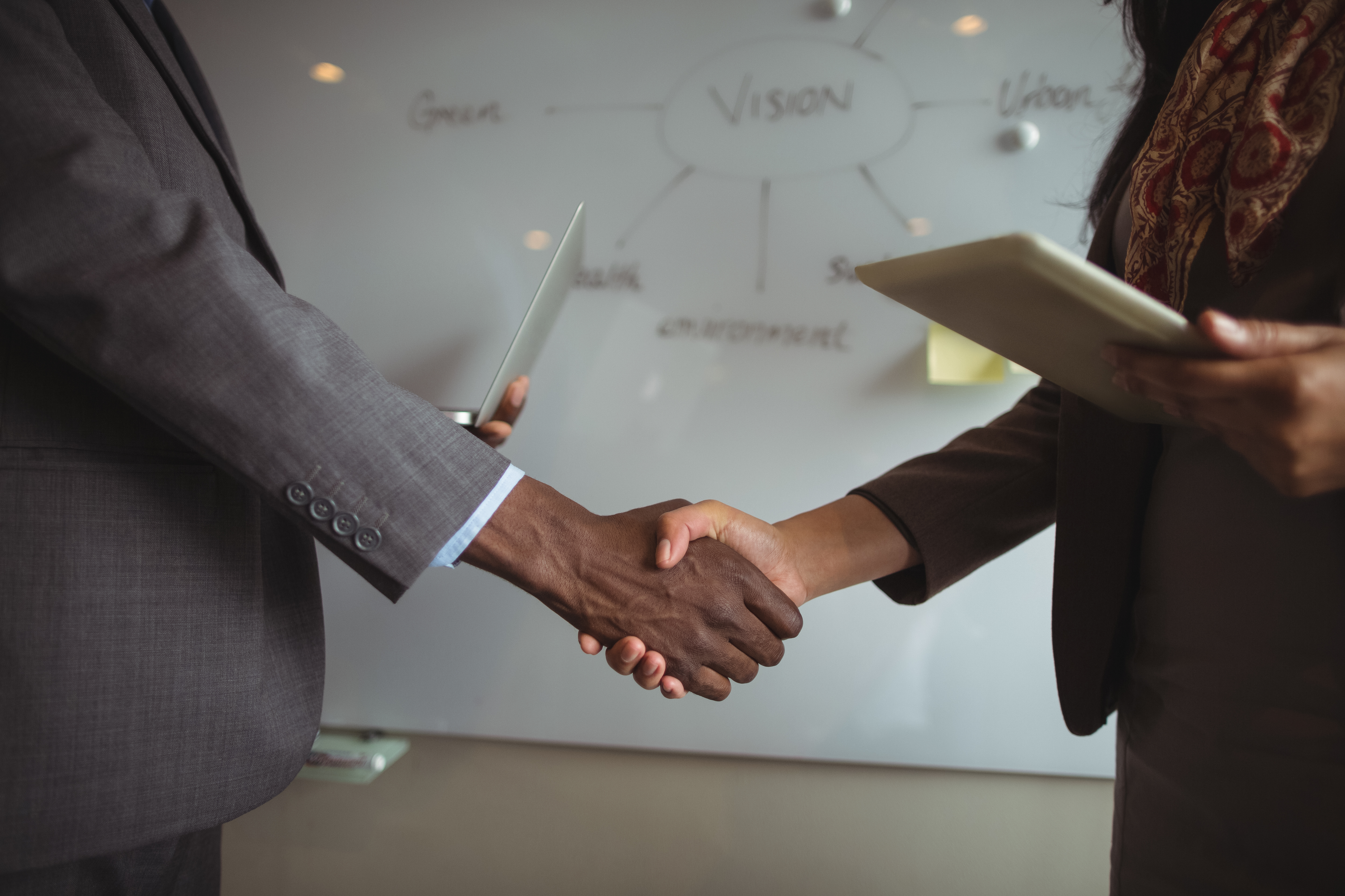 Mid section of businessman and a colleague shaking hands in office