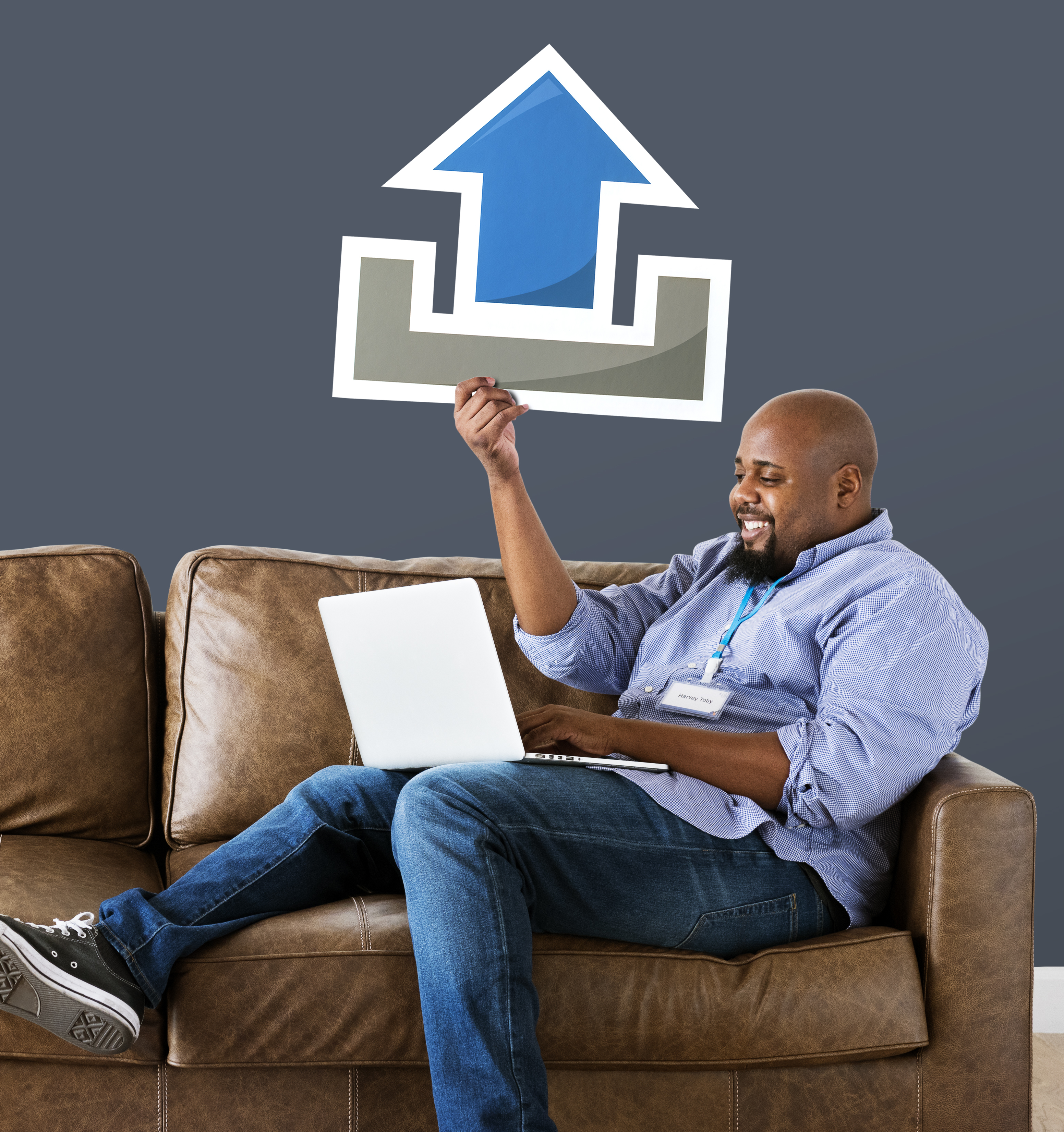Man using a laptop and holding an upload icon