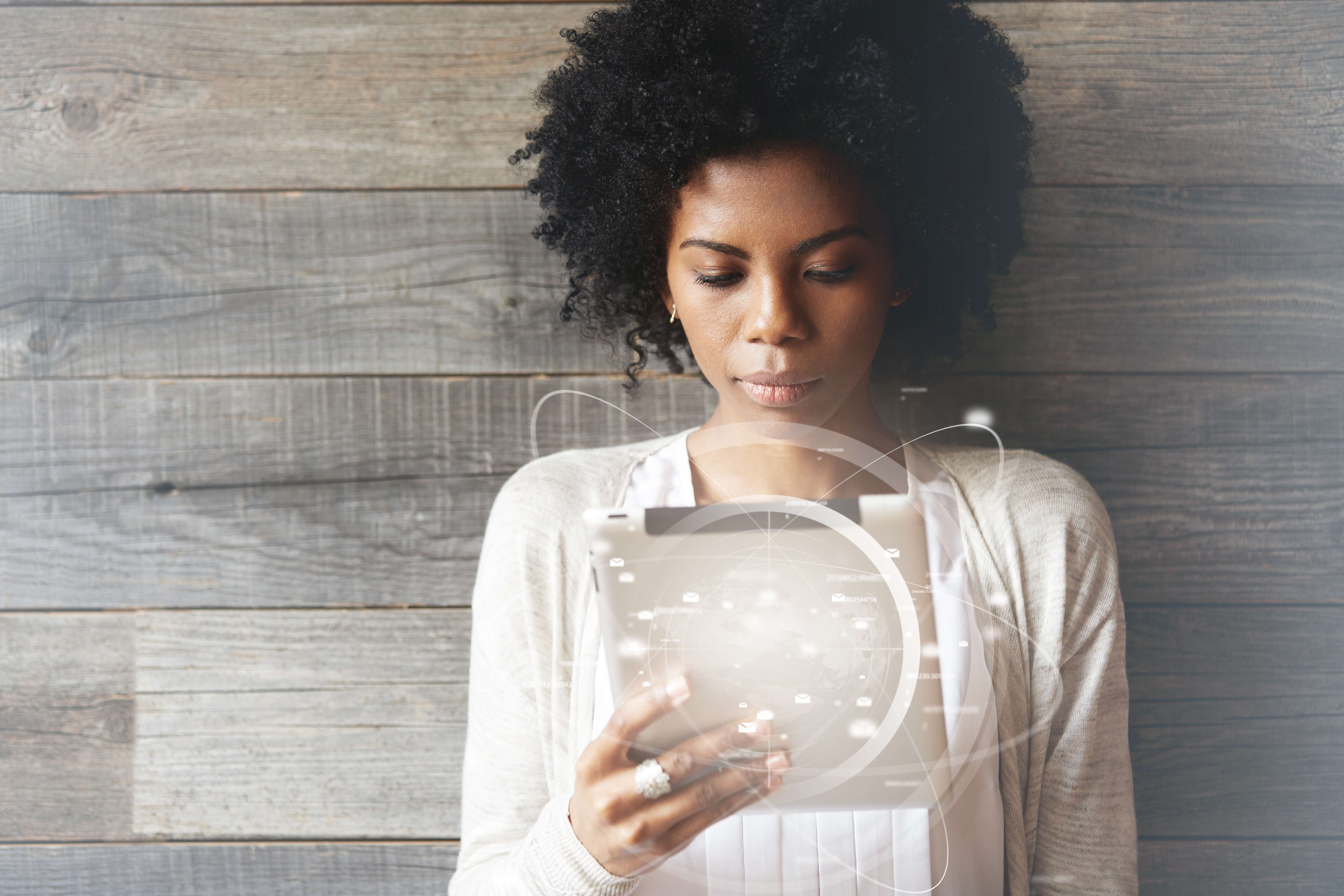 Futuristic technology and communication. Beautiful smiling black girl with Afro hairstyle using digital tablet pc or touch pad, checking email or typing message. Worldwide connection interface