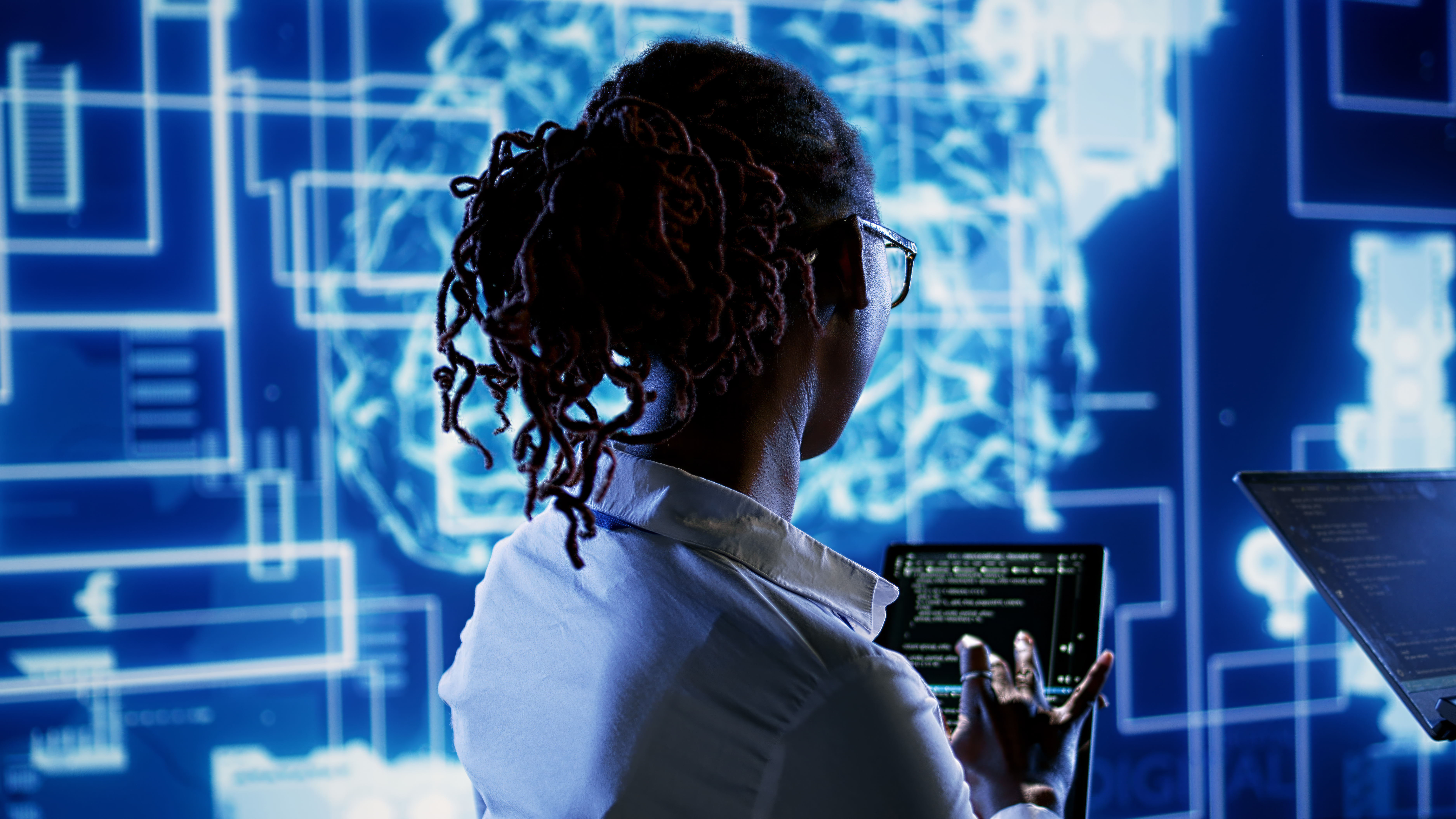Engineering coworkers updating AI systems, writing intricate binary code scripts on tablet and laptop. Trained technicians using programming to upgrade artificial intelligence simulation model