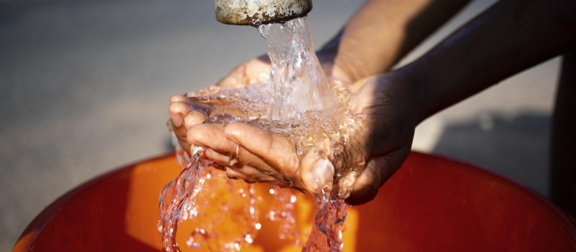 african-woman-pouring-water-recipient-outdoors
