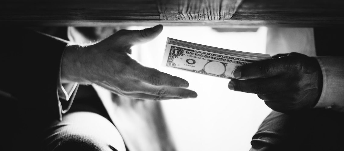 Hands passing money under the table corruption and bribery