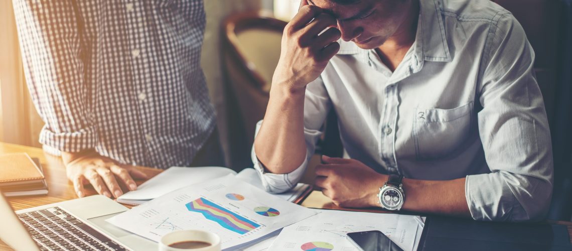 Serious young businessman looking at financial report seem like something mistake with his boss in office.