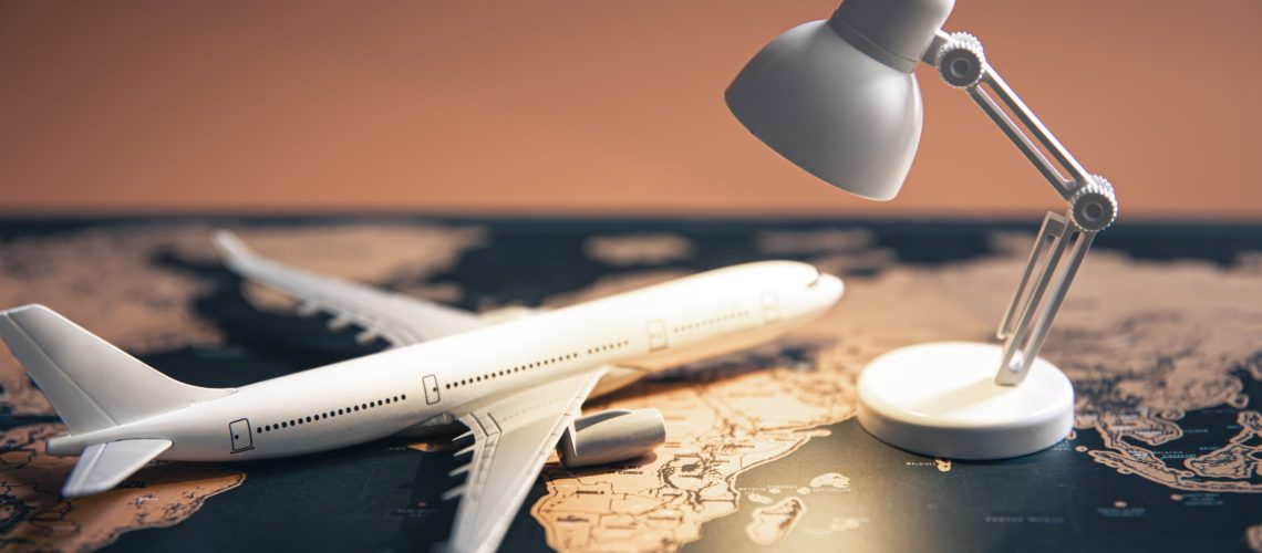 A small table lamp and a plane on a world map, travel concept.